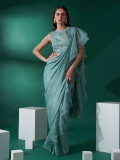 This is a two-piece sea green pre draped ruffle saree set from the Suruchi Parakh collection. The sea green pre draped ruffle saree in georgette crepe is paired with a hand-embroidered blouse. The satin base blouse has padding, and a cut-out detail at the back with hook opening. There is beautiful floral hand-embroidery and thread work all over the blouse with buttis. This sea green pre draped ruffle saree set is crafted in georgette crepe, organza and satin materials. Ruffle Saree Blouse, Ruffle Saree Designs, Online Shopping Sarees, Lehenga Gown, Ruffle Saree, Drape Saree, Purple Satin, Blouse For Women, Cape Dress