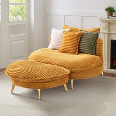 a yellow chaise lounge with pillows on it in front of a fireplace