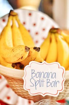 bananas in a bowl on a table with a sign that says banana split bar next to it