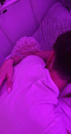 a woman laying in bed under a purple light