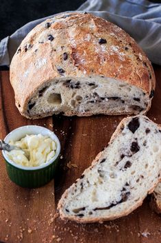 a loaf of bread sitting on top of a wooden cutting board next to a bowl of butter