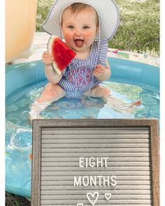 a baby sitting in a pool holding a piece of watermelon with the words eight months written on it