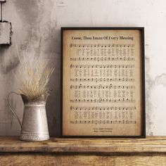 an old sheet music score is displayed next to a vase with dried grass in it