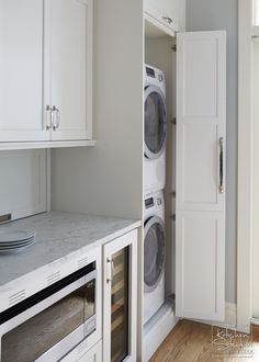 a washer and dryer in a small room with white cabinets on the wall