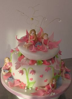 a three tiered cake decorated with fairy figurines