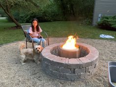 a woman sitting in a chair next to a fire pit with a dog on it