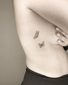 a woman's stomach with two small butterflies on her left side ribcage