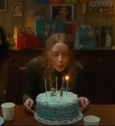 a girl blowing out the candles on her birthday cake while another girl looks at it