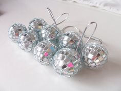 several shiny disco ball ornaments on a white surface