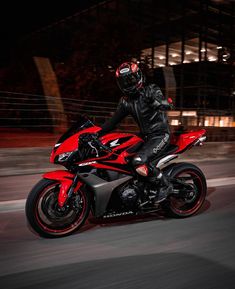 a man riding on the back of a red motorcycle