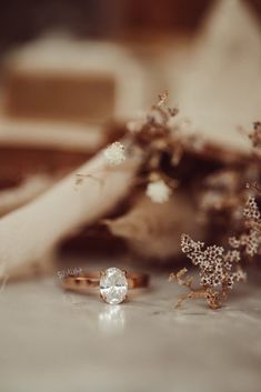 two engagement rings sitting on top of a table next to some flowers and other items