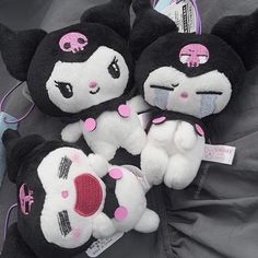 three black and white hello kitty stuffed animals on a gray blanket with tags attached to them