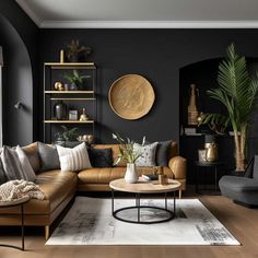 a living room with black walls and wooden flooring, leather couches, potted plants and round coffee table