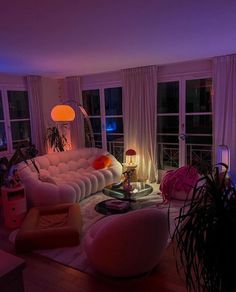 a living room filled with lots of furniture next to tall windows and lights on the ceiling