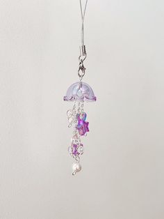 a purple and white necklace hanging from a silver chain on a hook with beads attached to it