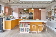 a kitchen with yellow cabinets and white counter tops next to a tall book shelf filled with books