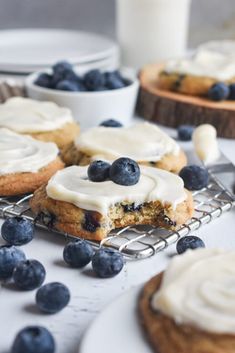 blueberry cookies with icing and fresh blueberries on a cooling rack in the background