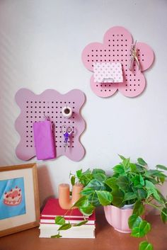 a wooden table topped with a potted plant next to two pink wall hangings