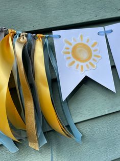 some ribbons are hanging on the side of a wooden building with two sun banners attached to it