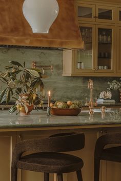 a kitchen counter with two stools and a bowl of fruit on the counter top