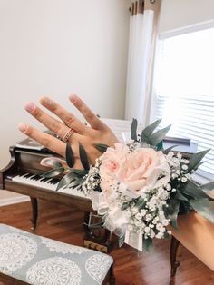 two hands reaching out to touch a bouquet of flowers in front of an open piano