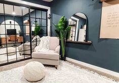 a living room filled with furniture and mirrors on the wall next to a plant in a vase