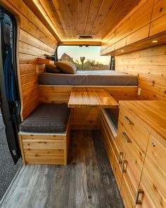 the interior of a van with wooden walls and drawers on each side, including a bed