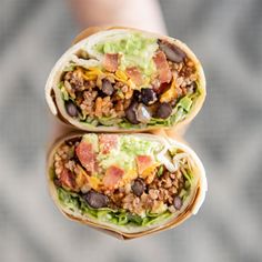 two burritos filled with meat, beans and cheese on top of each other