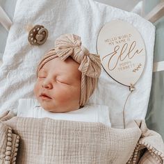 a newborn baby wrapped in a blanket next to a plaque