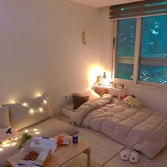 a bed room with a neatly made bed next to a large window and lights on the wall