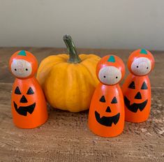 an orange pumpkin and three wooden figures on a table