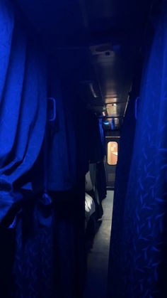 the inside of a bus with blue curtains and dark lighting on it's windows