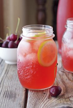 a jar filled with liquid next to some cherries