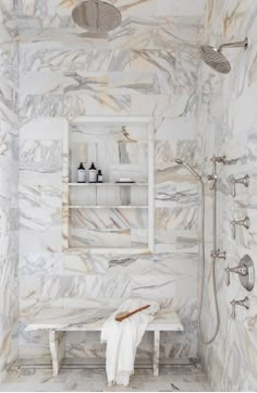 a bathroom with marble walls and flooring, including a white bench in the shower