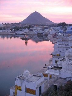 the water is calm and full of white buildings with mountains in the backgrouds