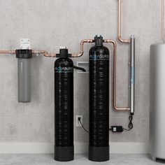 two water softeners are shown in front of a wall with exposed piping