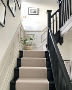 there is a black and white staircase with pictures on the wall