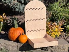 a wooden chair sitting next to two pumpkins on top of a stone slab in a garden