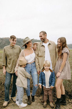 a group of people standing next to each other on a dirt road in the middle of a field