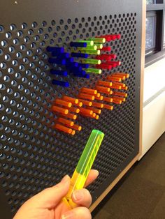 a person is holding a pen in front of a wall with colored arrows on it