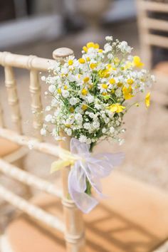 a bouquet of daisies and baby's breath tied to a chair