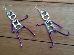 two pairs of purple wire hang from the ends of earrings on a wooden surface, with metal hooks attached to them