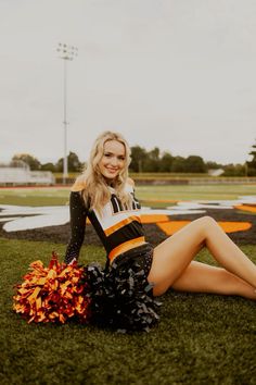 a cheerleader sitting on the ground with her pom poms