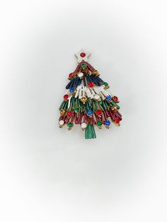 a multicolored christmas tree brooch on a white background