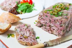 a plate with meat, bread and vegetables on it next to a knife and fork