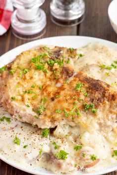 a white plate topped with meat covered in gravy and garnished with parsley