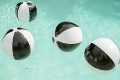 three black and white beach balls floating in the water