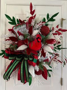 a christmas wreath on the front door decorated with red and white feathers, holly leaves, snowflakes and berries