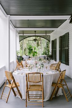 an outdoor dining area with white table cloths and wooden chairs