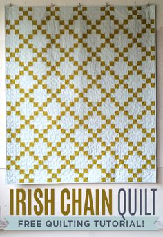 a white and yellow quilt hanging on the wall next to a sign that says irish chain quilt